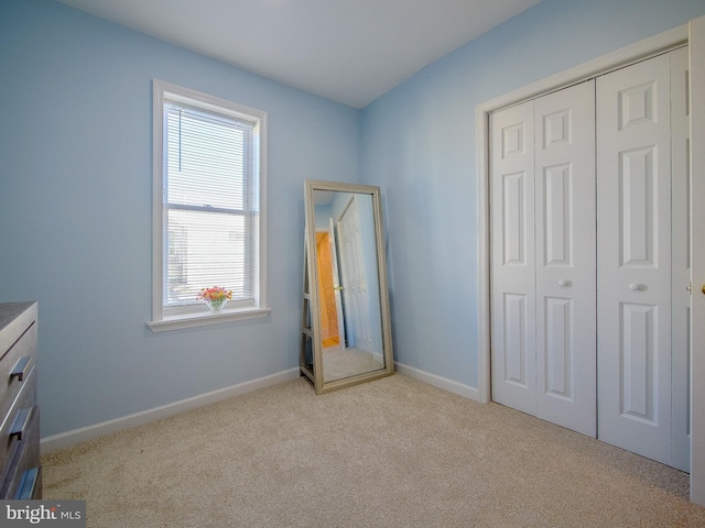 unfurnished bedroom featuring light carpet and a closet