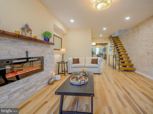 living room featuring a stone fireplace and wood-type flooring