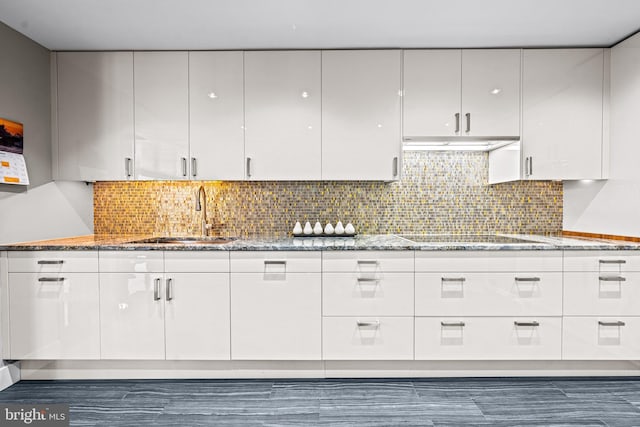 kitchen featuring white cabinets, backsplash, black electric cooktop, and sink