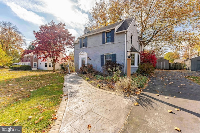 view of front of home featuring a front lawn and a storage shed