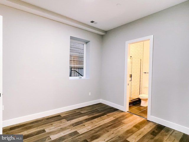 unfurnished bedroom with dark hardwood / wood-style flooring and ensuite bath