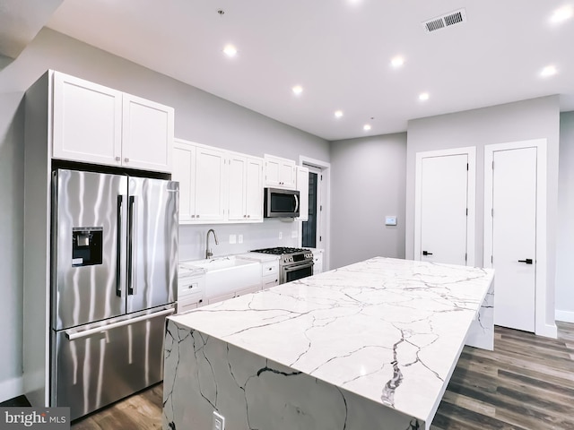 kitchen featuring sink, a center island, white cabinetry, stainless steel appliances, and dark hardwood / wood-style floors