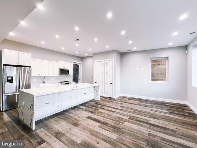 kitchen featuring a large island, appliances with stainless steel finishes, wood-type flooring, and white cabinets