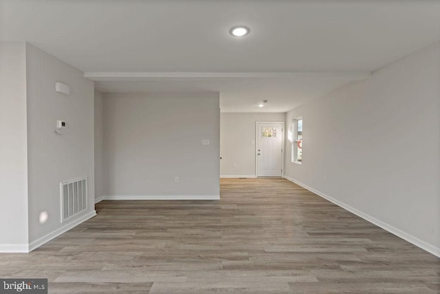 unfurnished room featuring wood finished floors, visible vents, and baseboards