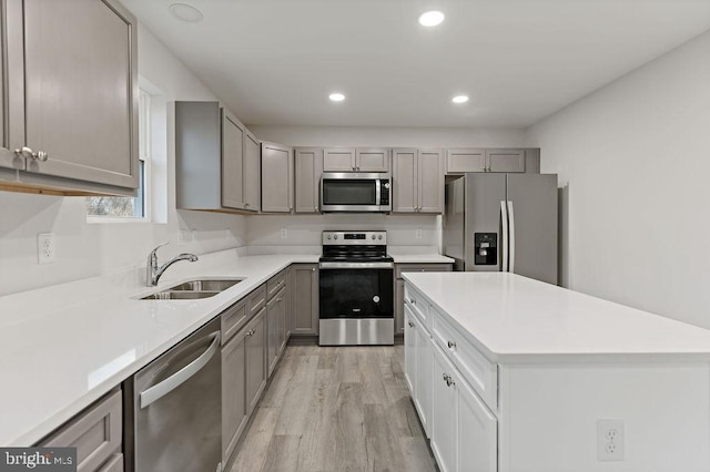 kitchen with gray cabinets, sink, appliances with stainless steel finishes, and light hardwood / wood-style floors