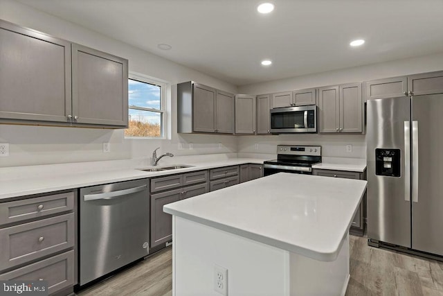 kitchen with light hardwood / wood-style flooring, stainless steel appliances, sink, gray cabinets, and a center island