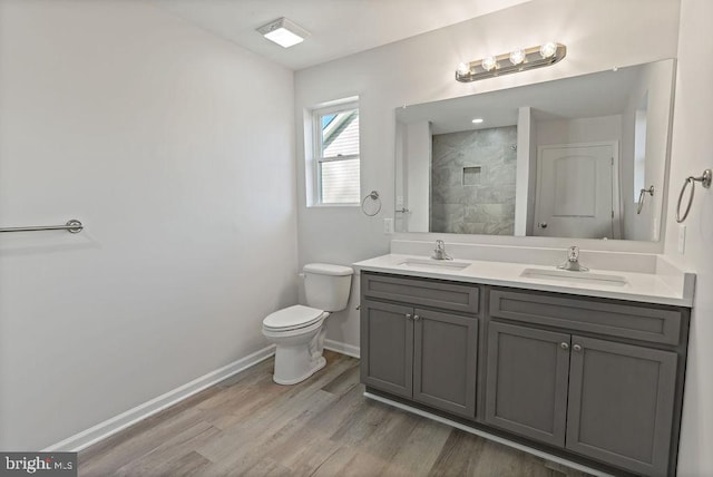 bathroom featuring toilet, hardwood / wood-style floors, vanity, and a tile shower