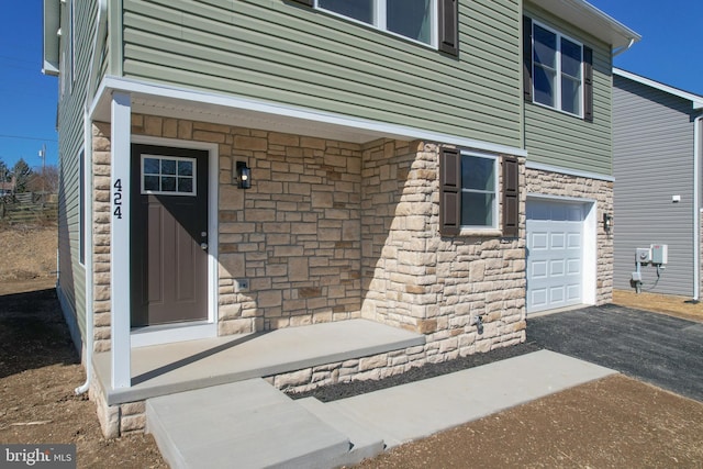 property entrance featuring stone siding and a garage