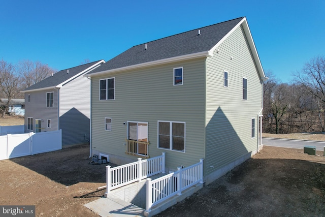 rear view of house featuring fence and roof with shingles