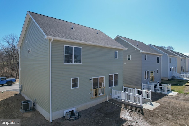 back of house featuring a deck, central AC, and roof with shingles