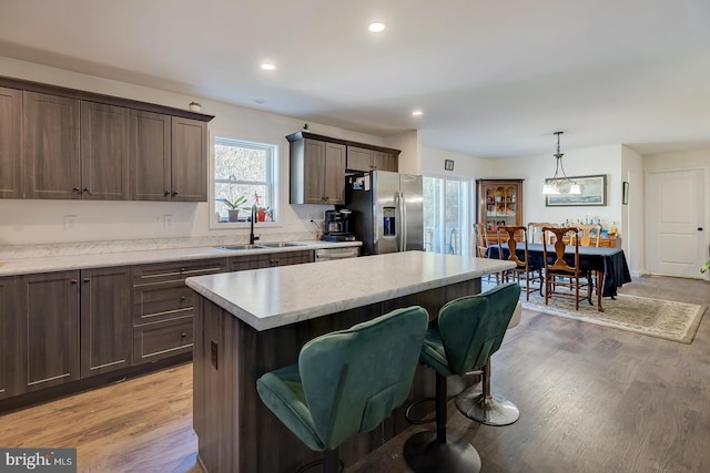 kitchen featuring a center island, sink, decorative light fixtures, light wood-type flooring, and stainless steel fridge