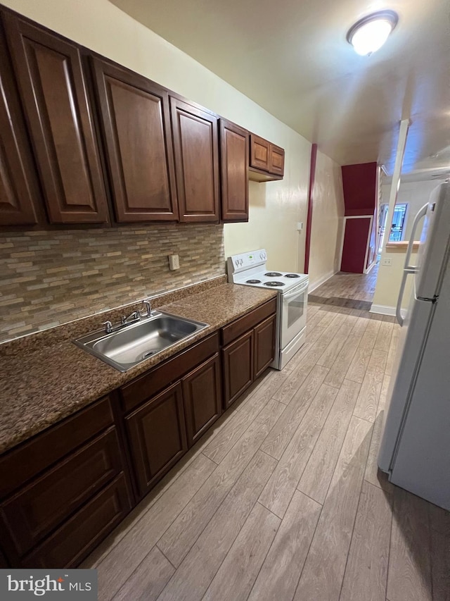 kitchen with dark brown cabinetry, sink, backsplash, white appliances, and light wood-type flooring