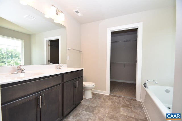 bathroom featuring vanity, toilet, and tiled tub