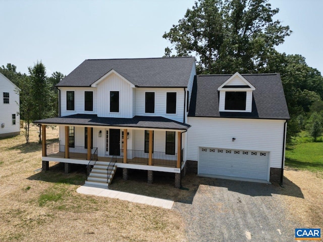 view of front of home featuring a garage, covered porch, and a front yard