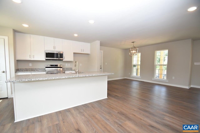 kitchen with dark hardwood / wood-style flooring, white cabinetry, stainless steel appliances, and a kitchen island with sink