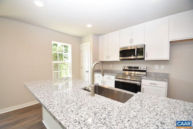 kitchen with white cabinetry, dark hardwood / wood-style flooring, light stone countertops, and stainless steel appliances