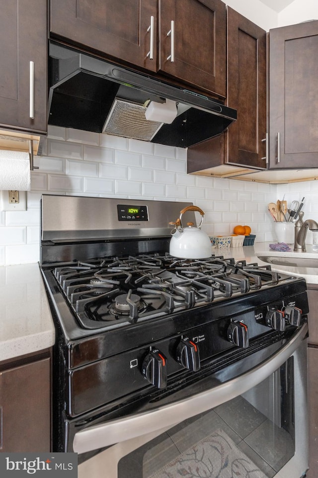 kitchen with decorative backsplash, stainless steel gas range oven, dark brown cabinetry, sink, and tile patterned flooring