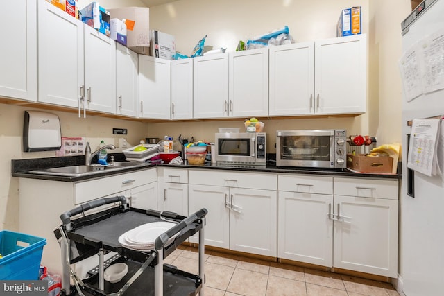 kitchen featuring sink, white cabinets, white refrigerator with ice dispenser, and light tile patterned floors