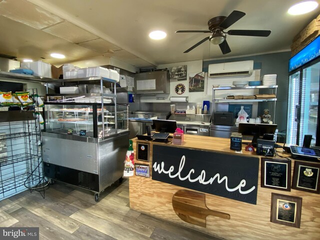 interior space featuring hardwood / wood-style floors, a wall unit AC, and ceiling fan