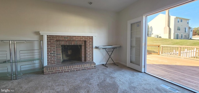 unfurnished living room featuring carpet flooring and a brick fireplace