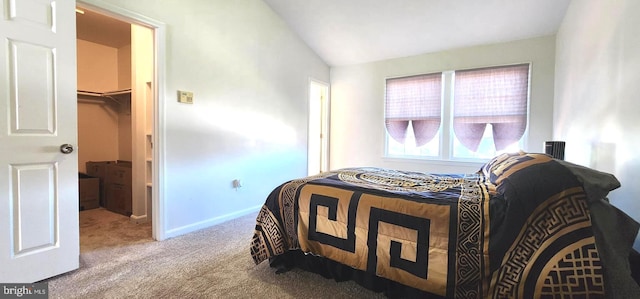 carpeted bedroom with a closet, lofted ceiling, and a walk in closet