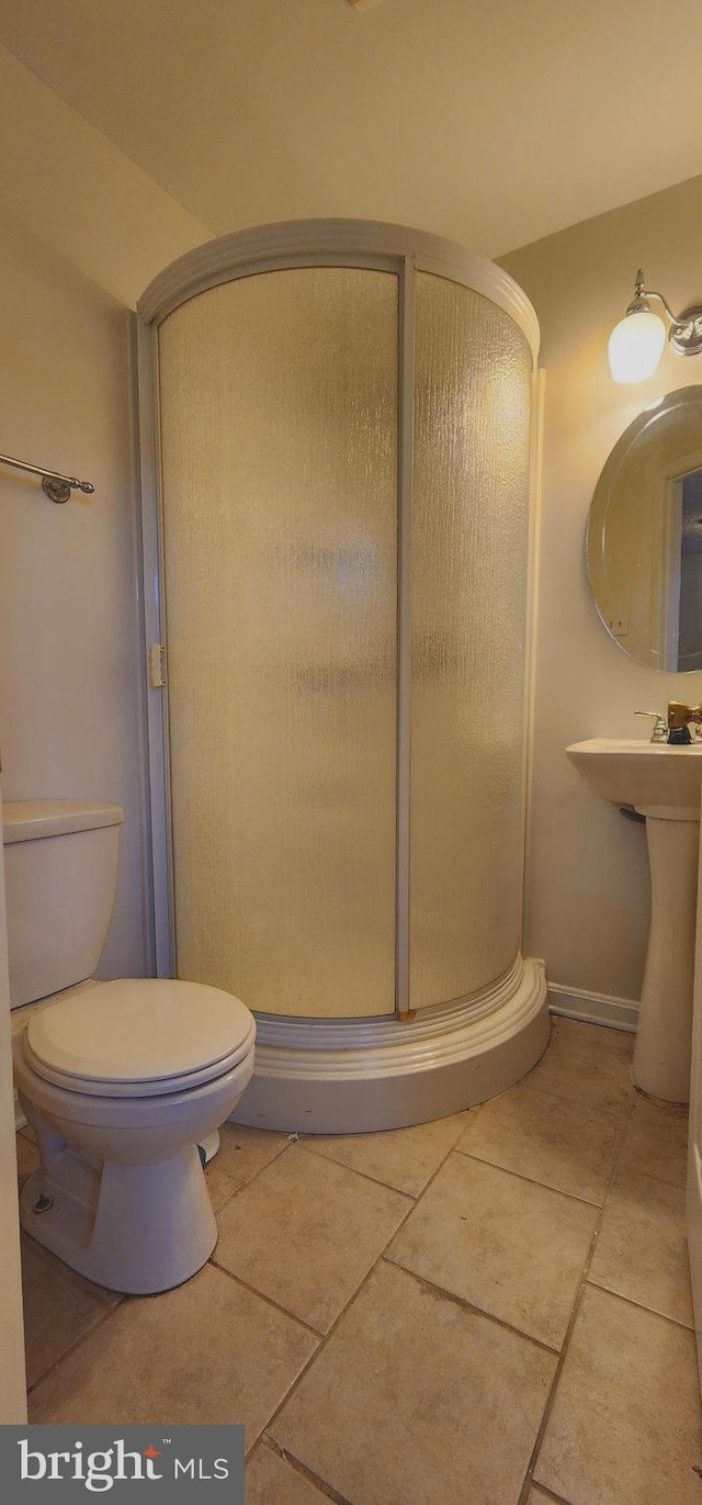 bathroom with toilet, walk in shower, and tile patterned floors