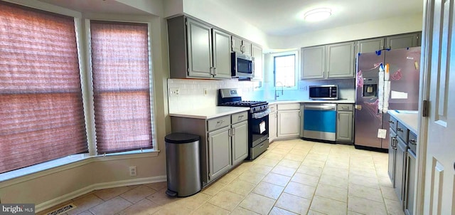 kitchen featuring gray cabinets, decorative backsplash, and stainless steel appliances