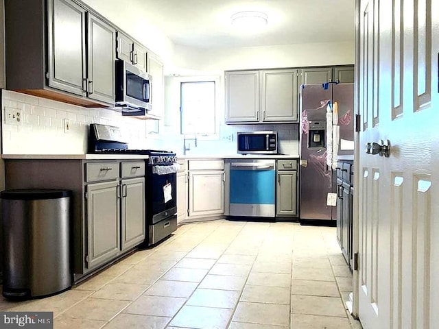 kitchen featuring gray cabinets, decorative backsplash, stainless steel appliances, and light tile patterned floors