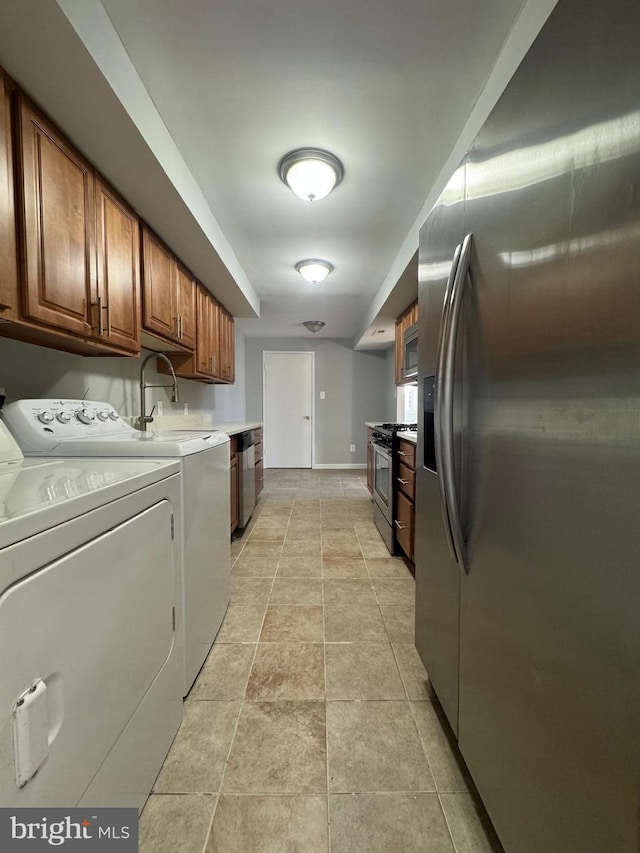 laundry area with light tile patterned floors, sink, and washing machine and clothes dryer