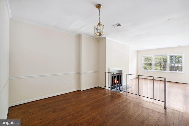 unfurnished living room with crown molding, dark hardwood / wood-style floors, and a chandelier