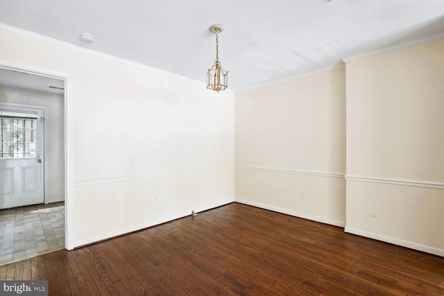 spare room with crown molding, dark hardwood / wood-style flooring, and a chandelier