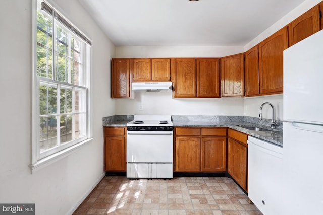 kitchen featuring sink, light stone counters, and white appliances