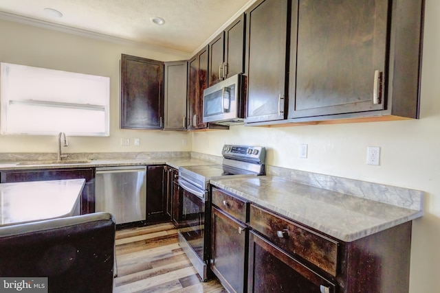 kitchen featuring appliances with stainless steel finishes, ornamental molding, light hardwood / wood-style floors, dark brown cabinetry, and sink