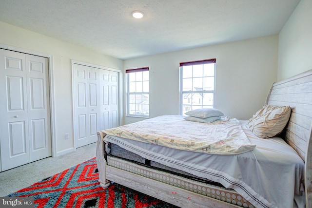 carpeted bedroom with a textured ceiling and two closets