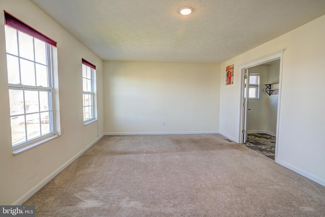 empty room with a textured ceiling and light colored carpet