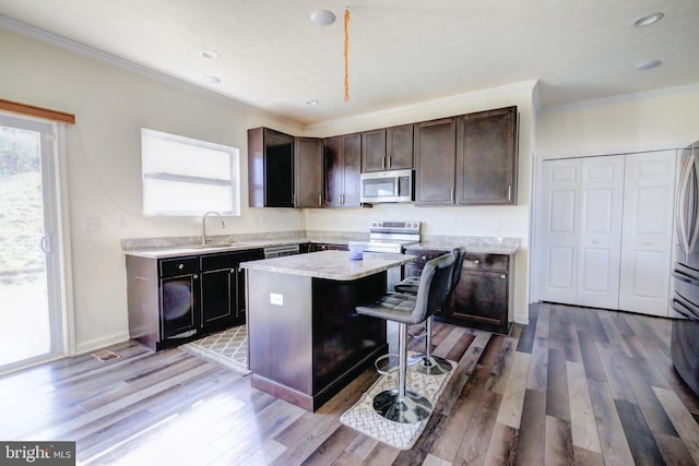 kitchen with sink, stainless steel appliances, a center island, and light wood-type flooring