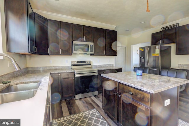 kitchen featuring dark brown cabinets, dark hardwood / wood-style flooring, a kitchen island, sink, and stainless steel appliances