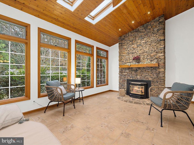 interior space with a stone fireplace, vaulted ceiling with skylight, and wooden ceiling