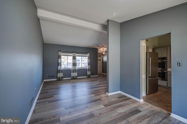 spare room featuring light hardwood / wood-style floors and beam ceiling