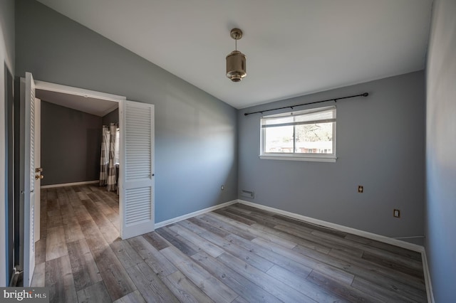 unfurnished room with vaulted ceiling and hardwood / wood-style flooring