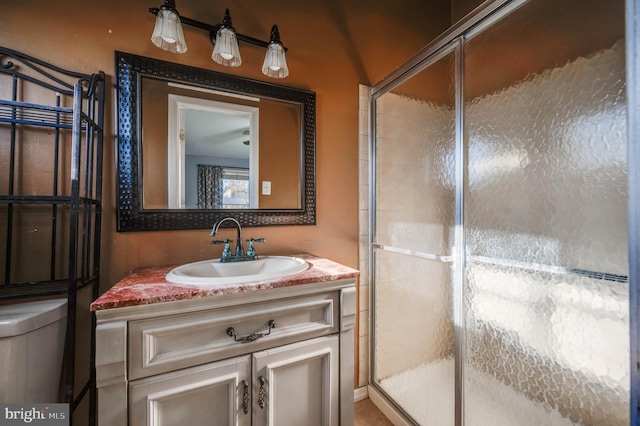 bathroom with toilet, vanity, and a shower with door