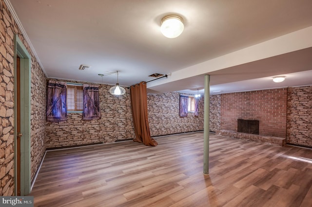 basement featuring a fireplace, ornamental molding, and hardwood / wood-style floors