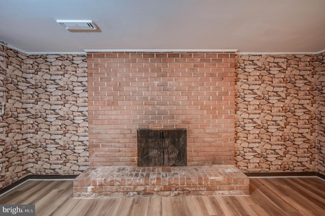 room details featuring hardwood / wood-style flooring, ornamental molding, and a brick fireplace