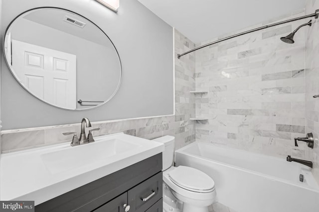 full bathroom with tile walls, tiled shower / bath, toilet, and vanity