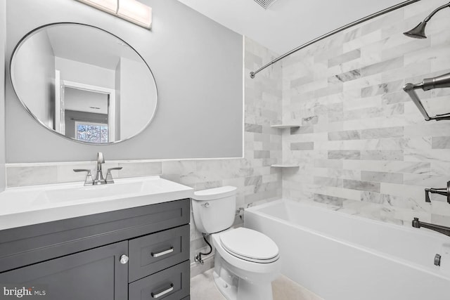 full bathroom featuring tile walls, vanity, tiled shower / bath combo, and toilet