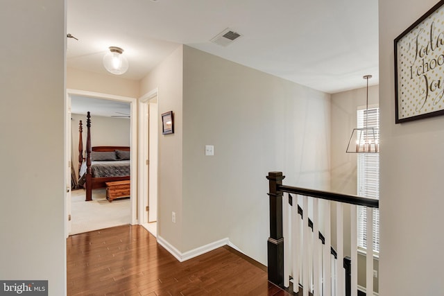 hall featuring an inviting chandelier and dark wood-type flooring