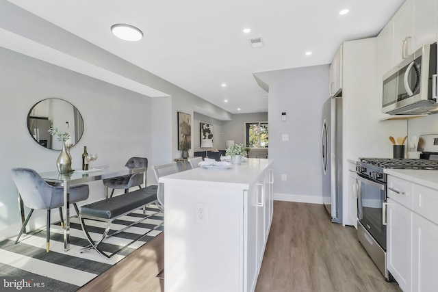 kitchen featuring a kitchen island, appliances with stainless steel finishes, light hardwood / wood-style flooring, and white cabinets