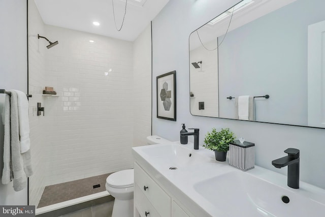 bathroom featuring vanity, tiled shower, toilet, and tile patterned floors