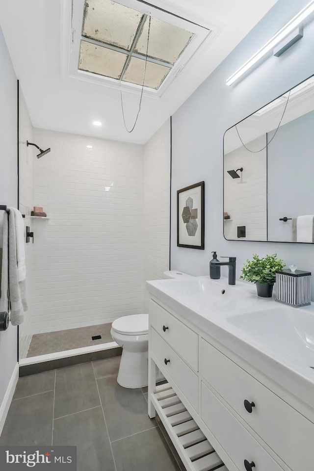 bathroom featuring toilet, tile patterned flooring, vanity, and tiled shower