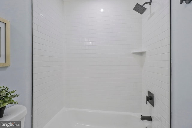 bathroom with toilet and tiled shower / bath combo